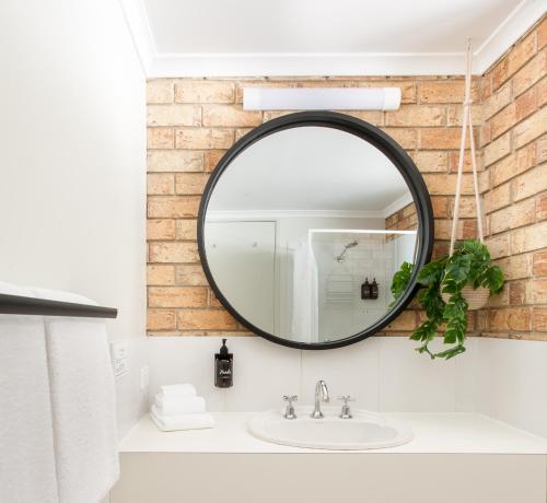 a bathroom with a sink, mirror, and a large mirror at Sunshine Coast Motor Lodge in Woombye