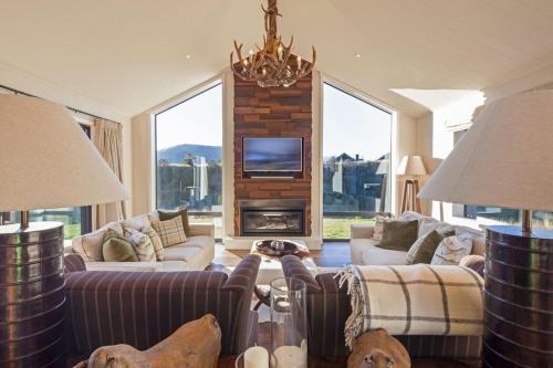 a living room with couches and a fireplace with a tv at Kawarau Lodge Ski Golf Or Relax In Style BBQ in Queenstown