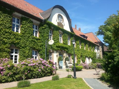 a building covered in ivy with a clock on it at Klosterhotel Wöltingerode in Goslar