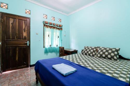 a blue bedroom with a bed and a window at Rock Garden Homestay & Resto in Tepus