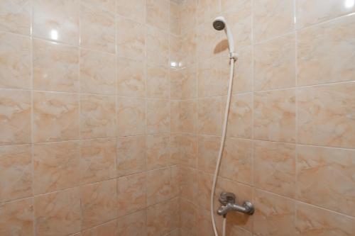 a shower with a hose in a bathroom at RedDoorz Syariah At Afifah Guest House near Bikasoga Sport Center in Bandung