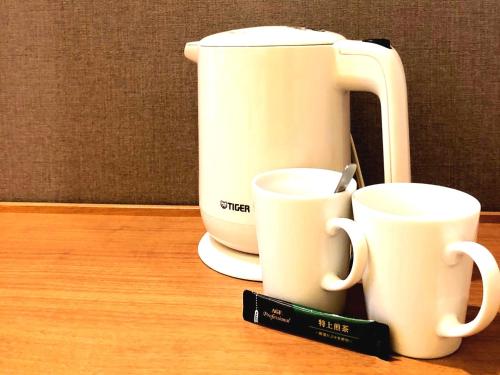 two white coffee cups sitting on a table at Hiroshima Tokyu REI Hotel in Hiroshima
