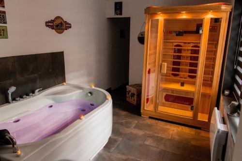 a bathroom with a tub and a glass door at Aux 3 Nuances Suites Privatives & Spa in Calais