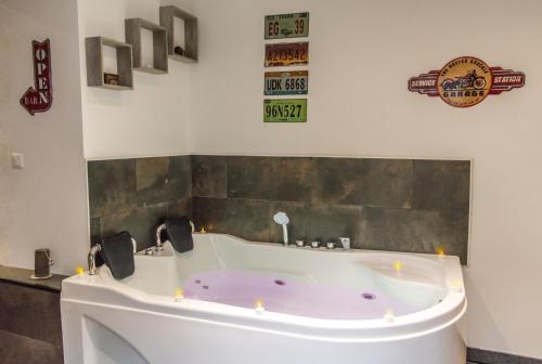 una vasca da bagno in un bagno con candele sul muro di Aux 3 Nuances Suites Privatives & Spa a Calais