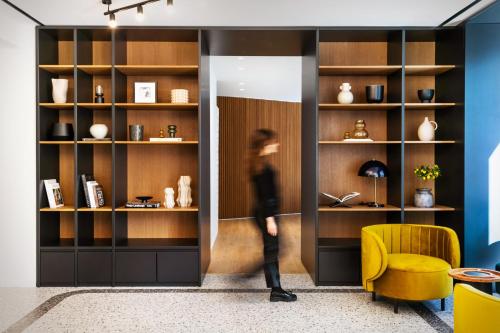 a woman is walking through a book shelf at Noa Hotel in Thessaloniki