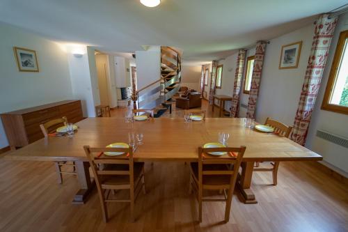 a dining room with a large wooden table and chairs at Vacancéole - Résidence Le Birdie in Giez