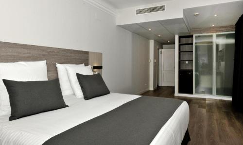 a bedroom with a large bed with white and gray pillows at Hotel Salobreña Suites in Salobreña