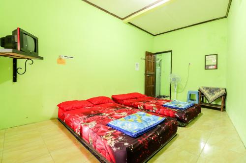 een woonkamer met twee rode banken en een tv bij Penginapan Roro Mendut Syariah in Magelang