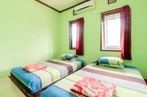 twee bedden in een kamer met groene muren en ramen bij Penginapan Roro Mendut Syariah in Magelang