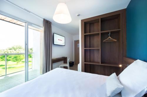 a bedroom with a large bed and a large window at B&B HOTEL Saint-Nazaire Pornichet in Saint-Nazaire