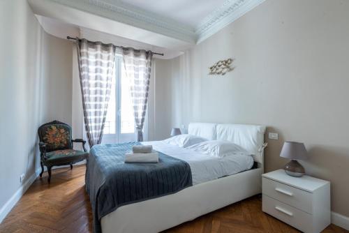 ein weißes Schlafzimmer mit einem Bett und einem Stuhl in der Unterkunft Londres in Nizza