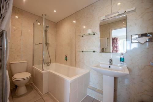 a bathroom with a sink and a toilet and a bath tub at Oakside Lodge Guest House in Canterbury