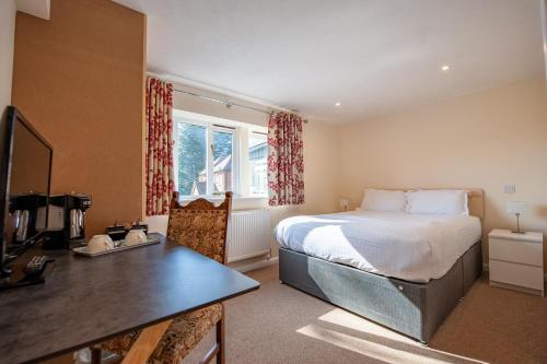 a bedroom with a bed and a desk in it at Oakside Lodge Guest House in Canterbury