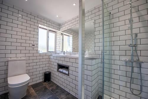 a white tiled bathroom with a toilet and a sink at Oakside Lodge Guest House in Canterbury