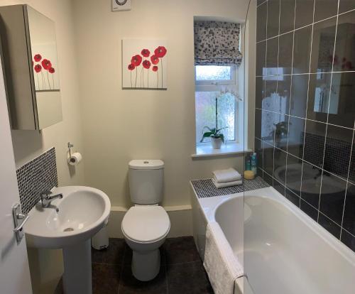 a bathroom with a toilet and a sink and a tub at Beachside Home - Sleeps 5 Garden Parking & Pets in Skegness
