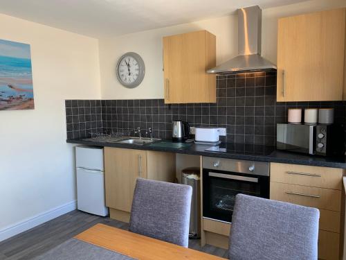 a kitchen with a sink and a clock on the wall at Balcony Apartment near Skegness Beach & Town in Skegness