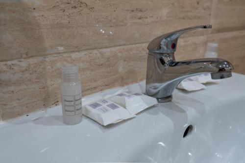 a bathroom sink with a bottle of mouthwash and a faucet at Стаи за гости ValenDa in Kirkovo