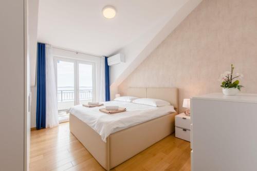 um quarto com uma cama e uma grande janela em Apartmani Krilo em Podstrana