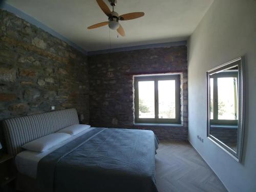 a bedroom with a bed and a ceiling fan at Villa Rokanes Glass Stone with Pool in Kouvéllai