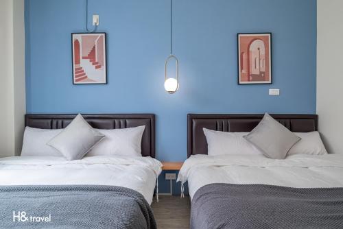 two beds in a room with a blue wall at H& Taitung Feng Lin Resort Hotel in Taitung City