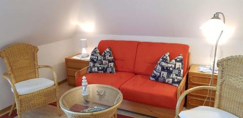 a living room with a red couch and two chairs at Ferienwohnung-Floppy-Hansi-OG-3 in Sankt Peter-Ording
