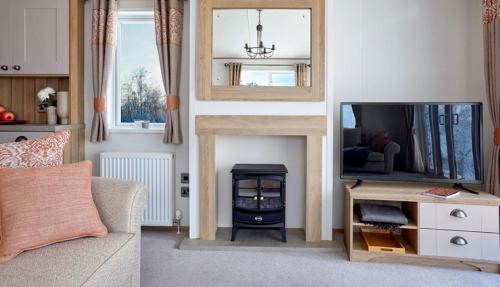 a living room with a television and a fireplace at Bluebell Lodge in South Cerney