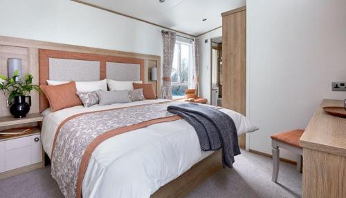 Un dormitorio con una cama grande y una ventana en Bluebell Lodge, en South Cerney