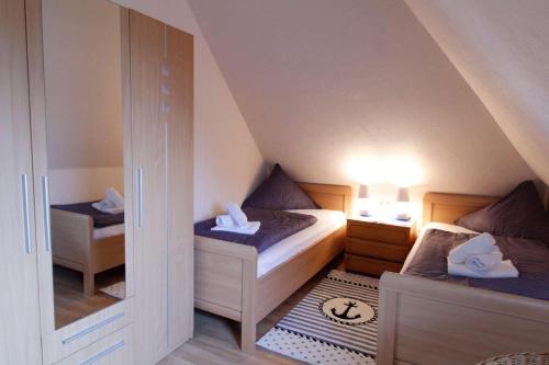 ein kleines Schlafzimmer im Dachgeschoss mit 2 Betten und einem Spiegel in der Unterkunft Ferienwohnung Floppy Hansi OG 2 in Sankt Peter-Ording