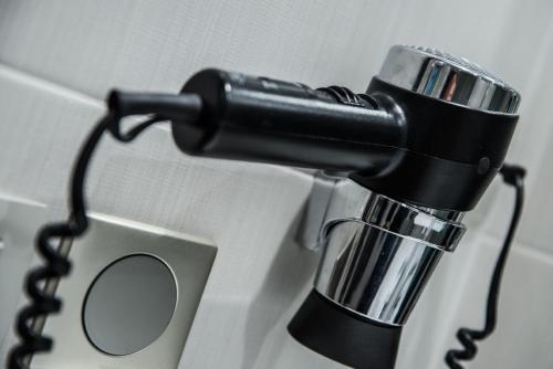 a black blow dryer hanging on a wall at Mercure Dinan Port Le Jerzual in Dinan