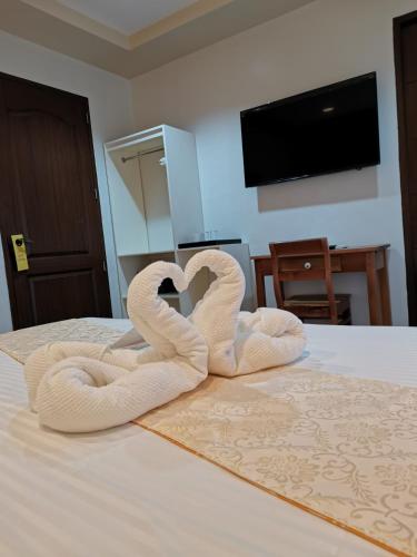 two towel swans forming a heart on a bed at Layang Layang Home in El Nido