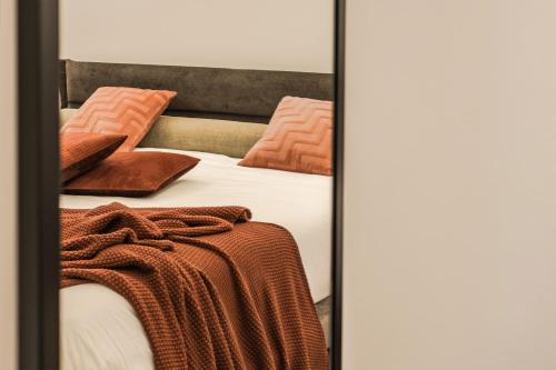 Una cama con almohadas naranjas y una manta. en Viale dei Lecci - Luxury rooms, en Francavilla Fontana