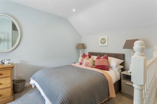 a bedroom with a bed with red pillows and a mirror at Acorn Cottage in Loughborough