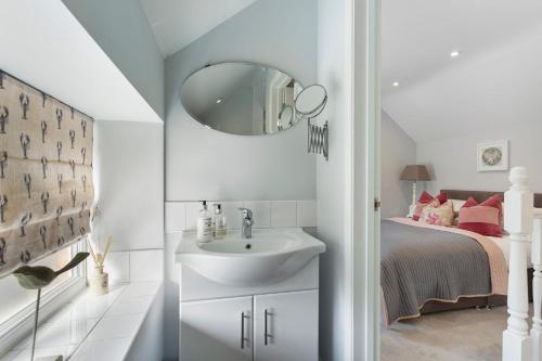 a white bathroom with a sink and a bed at Acorn Cottage in Loughborough