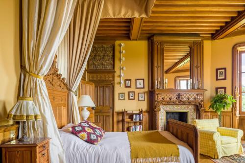 a bedroom with a canopy bed and a fireplace at Chateau LE BROSSAY in Renac