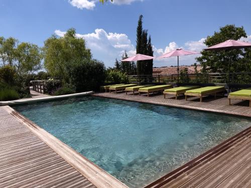 a swimming pool with chairs and umbrellas on a deck at Les Terrasses de Valensole in Valensole