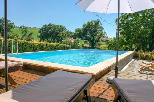 Larrazetにあるle Pigeonnier de Migouの椅子2脚と傘が備わったプール