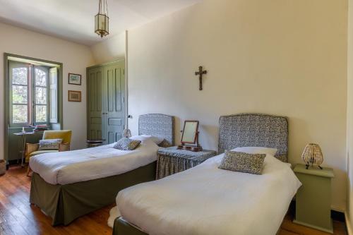 a room with two beds and a cross on the wall at Chateau LE BROSSAY in Renac