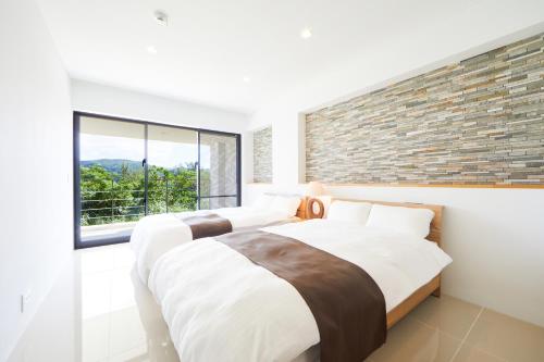two beds in a bedroom with a brick wall at E-horizon Resort Premium 瀬底D in Motobu