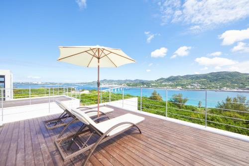 a patio with two chairs and an umbrella on a deck at E-horizon Resort Premium 瀬底D in Motobu