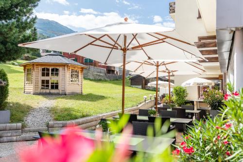 een patio met een parasol en een hondenhok bij Hotel Alpenhof in Unterbäch