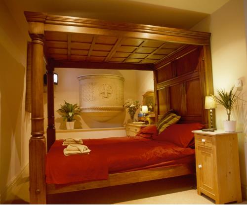 a bedroom with a canopy bed with red sheets at Mountain Church in Capel-Curig