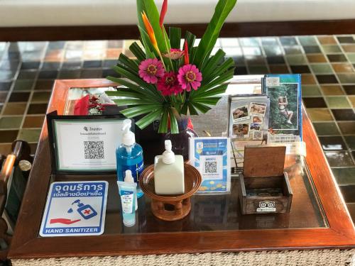 uma mesa com um vaso de flores e outros itens em Papai Country Lodge SHA em Ban Mae Pong