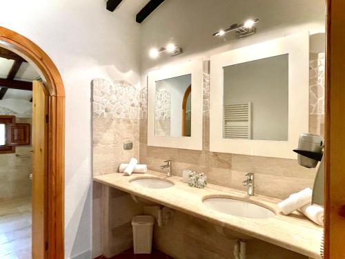 un baño con dos lavabos y dos espejos en Punta D'Acu Country Resort, en Arzachena