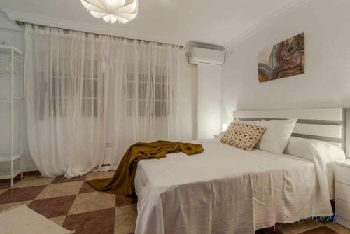 a bedroom with a white bed with a blanket on it at Suite con jacuzzi en el centro vistas y garaje in Huelva