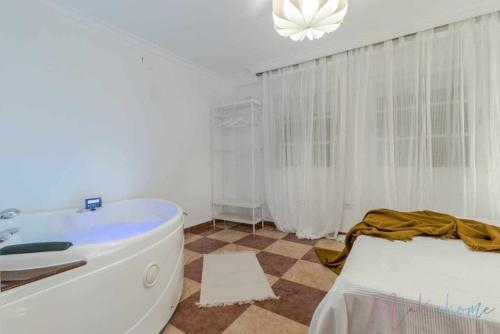a bathroom with a tub and a bed in it at Suite con jacuzzi en el centro vistas y garaje in Huelva