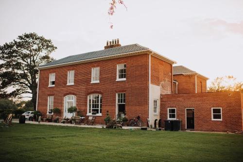 a large red brick building with a lawn in front of it at Reymerston Hall in Norwich