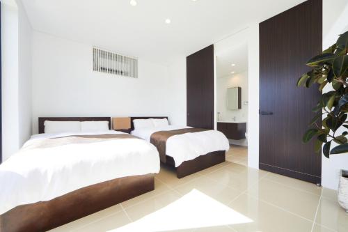a hotel room with two beds and a bathroom at E-horizon Resort Premium 瀬底E in Sesoko
