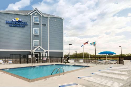 une piscine avec des chaises longues blanches en face d'un hôtel dans l'établissement Microtel Inn & Suites by Wyndham Georgetown Delaware Beaches, à Georgetown