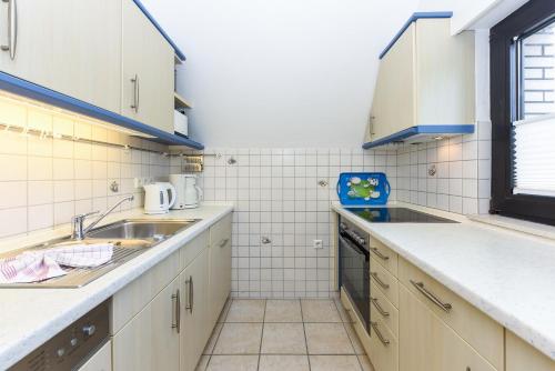 a kitchen with white cabinets and a sink at Ferienhaus Boje 13 in Neuharlingersiel