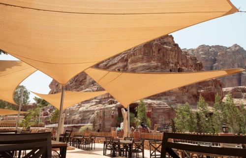 a group of tables and chairs with umbrellas at Petra Guest House Hotel in Wadi Musa